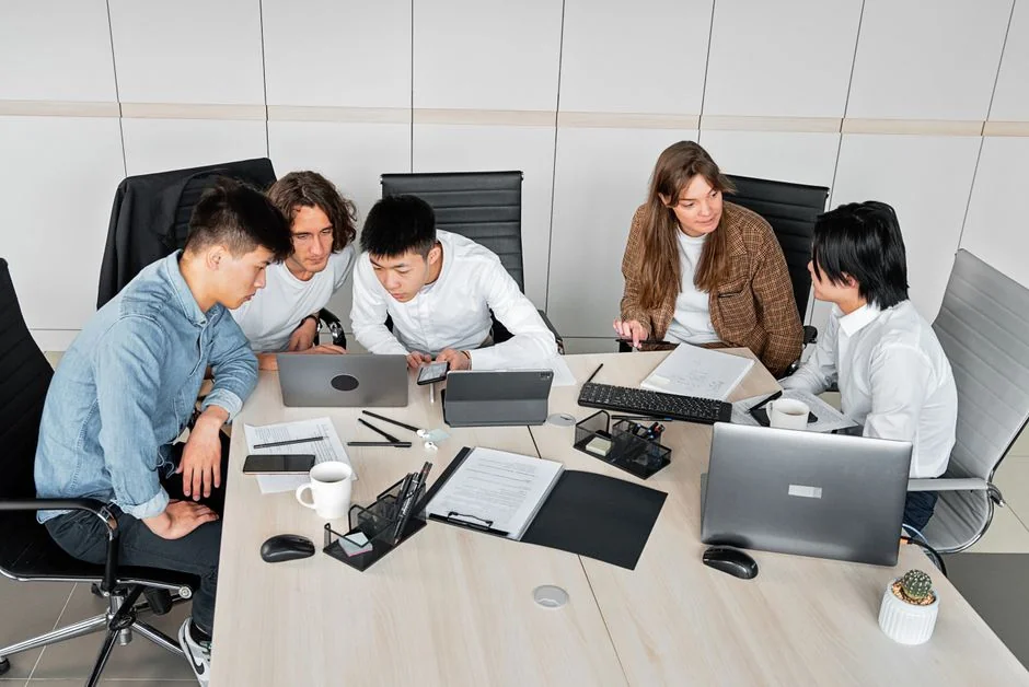 A diverse team collaborating on digital marketing strategies at a desk, using laptops and tablets.